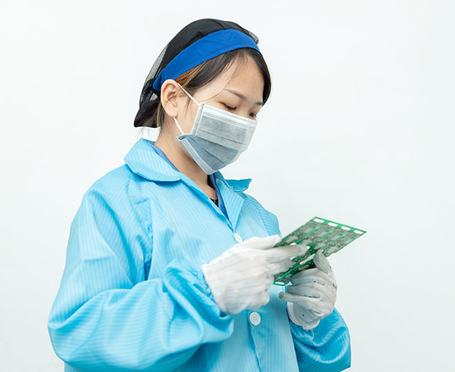 a female worker wearing a mask, a black hairnet, a suit of  blue clean room uniform, and a pair of white gloves.