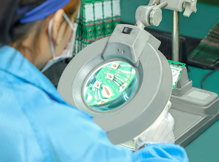 a worker checking a PCB's layout with a magnifying glass
