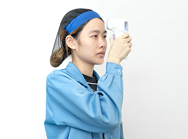 a female worker is testing an infrared thermometer's function