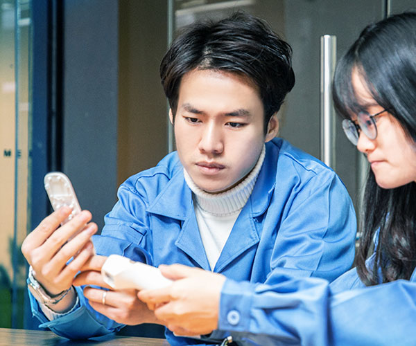 two engineers looking at the prototype of an infrared thermometer and discussing