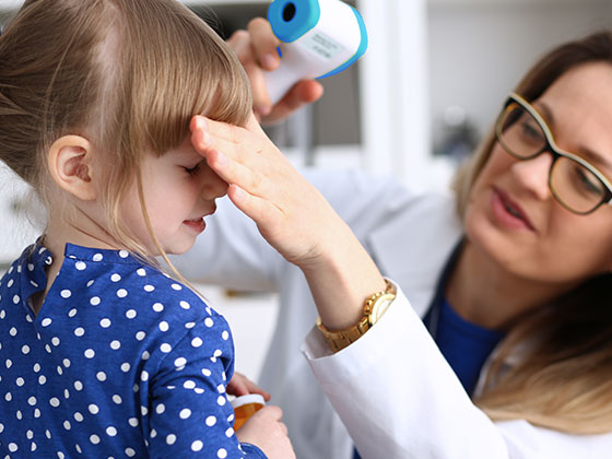 measuring a school kid's forehead temperature with an infrared thermometer